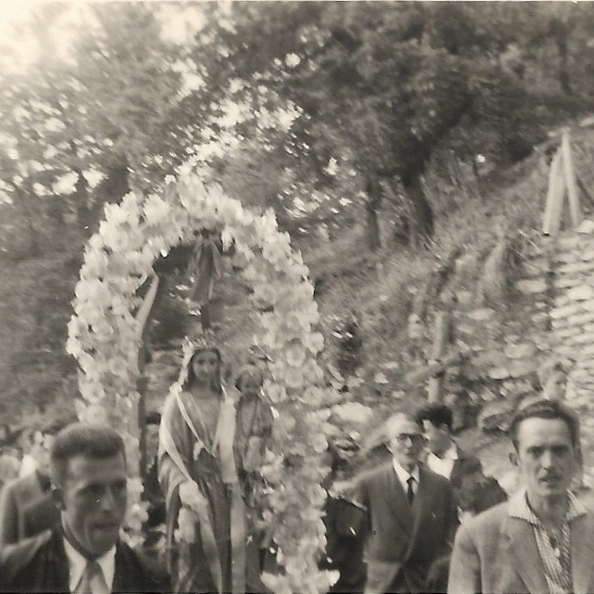 Procession de la Vierge sous un arc de fleurs dans un village corse